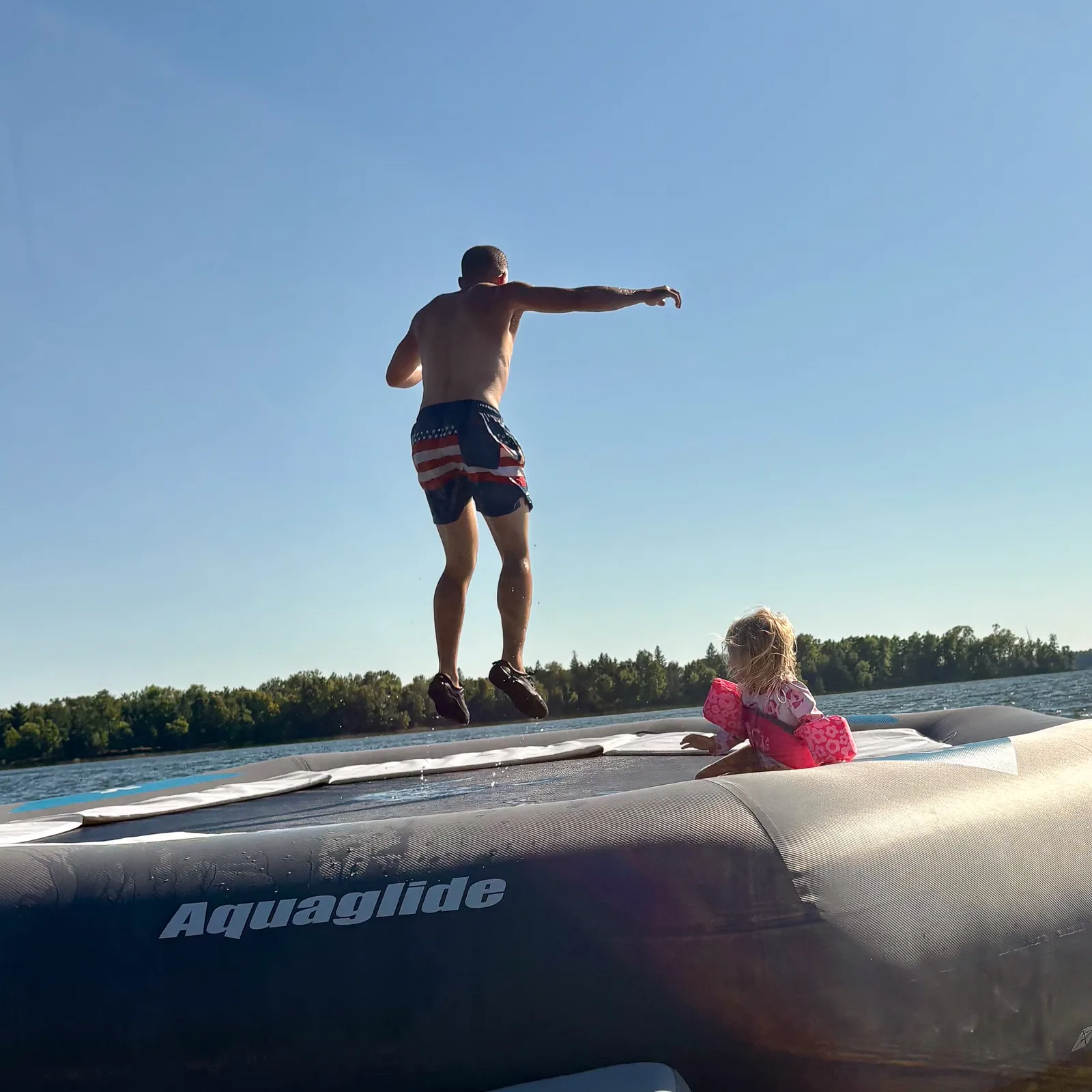 Dad and daughter on the water trampoline at the lake water park at Kohl’s Resort, a family resort near Bemidji, MN