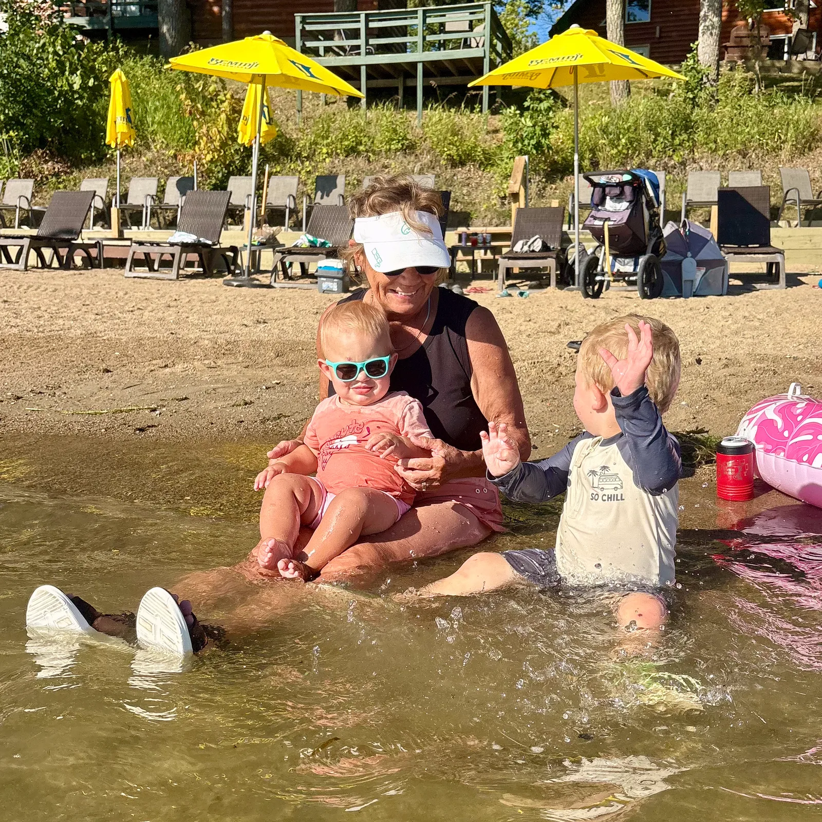 Grandma and little kids playing in the water at the sandy beach at Kohl’s Resort on Big Turtle Lake