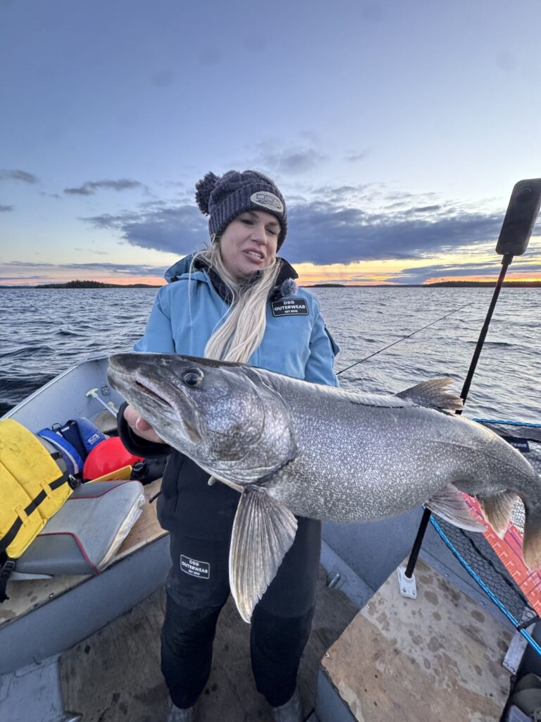 Angler holding a large lake trout at sunset on Kamuchawie Lake